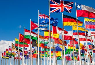 A photo taken of multiple country flags against the blue sky.
