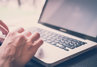 A photo focusing on a person’s hand typing on a laptop, with only the hand and keyboard visible to emphasize the action.
